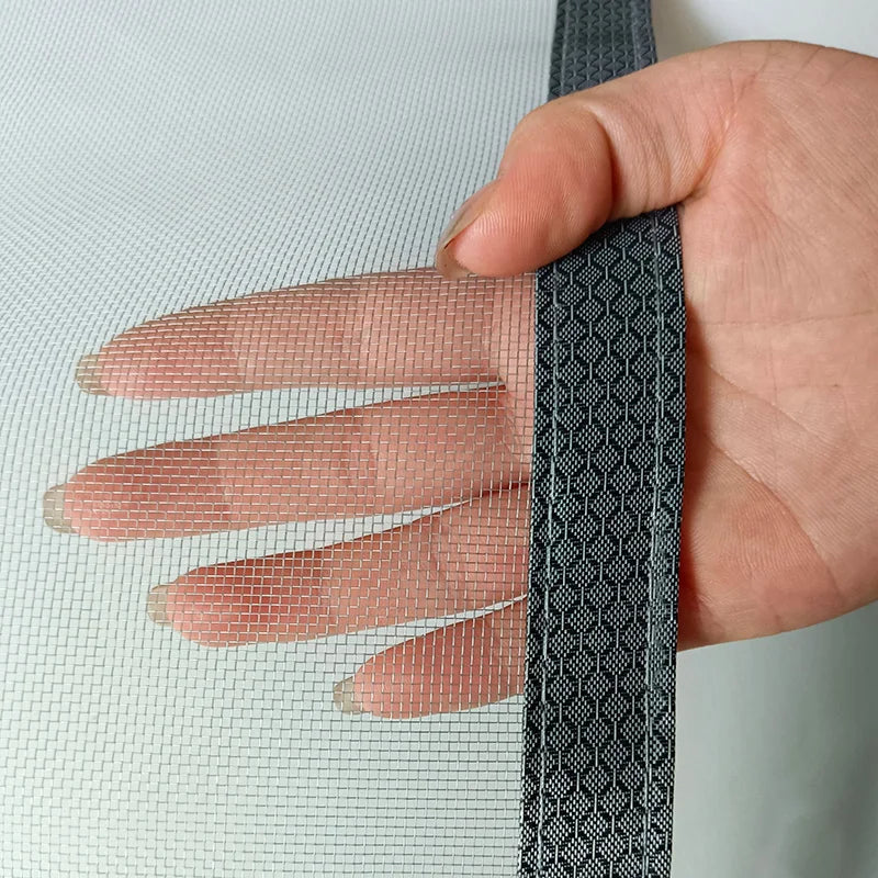 Hand holding a strip of black mesh fabric against a light background