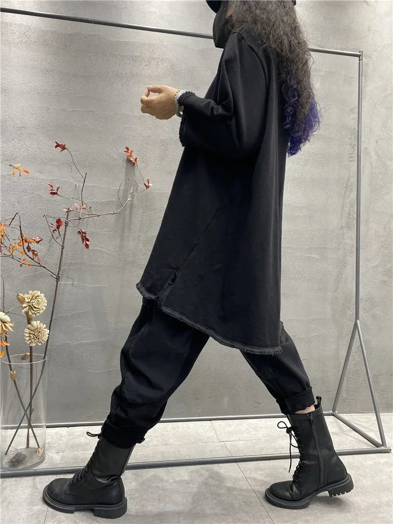 Womens plus size long sleeve top in black, long loose fit t-shirt with black pants against gray wall