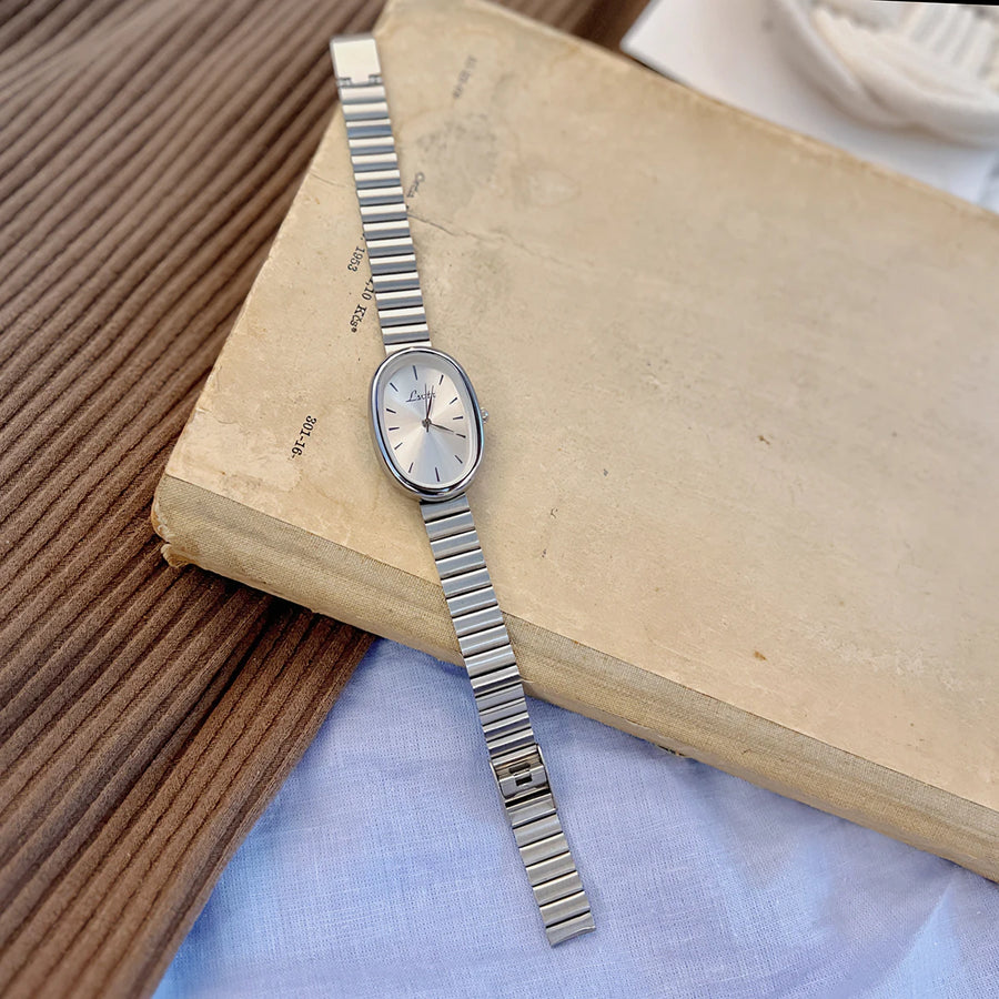 Silver watch on an open book with a textured surface