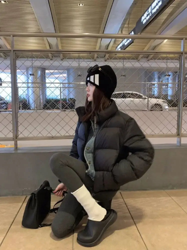 Woman wearing a cropped puffer jacket in a stylish outfit, sitting indoors