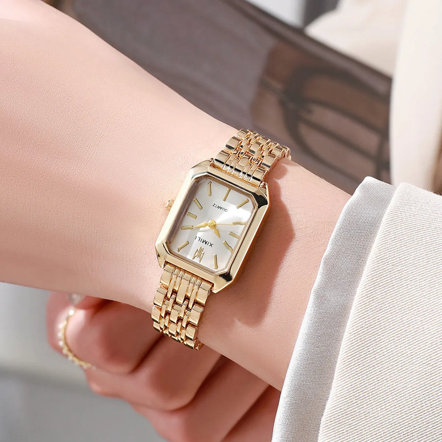 Women's gold quartz dress watch worn on wrist with blurred background