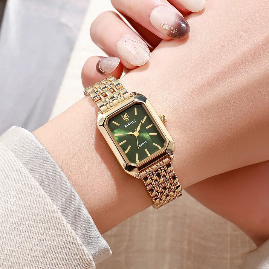 Close-up of women's gold quartz watch with green dial on wrist