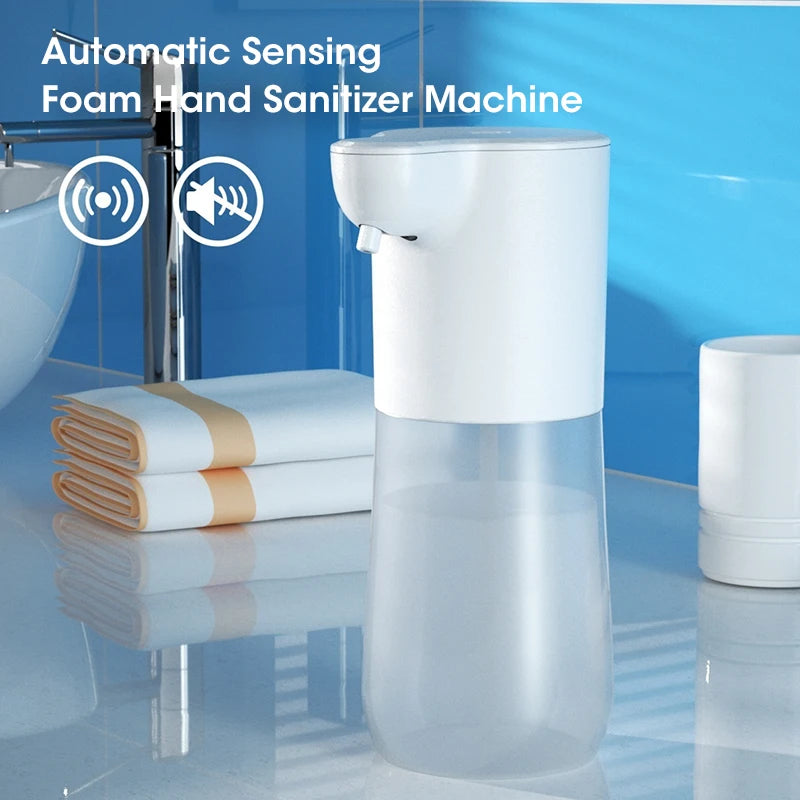 Automatic sensing foam hand sanitizer machine in a bathroom setting with towels and a sink.