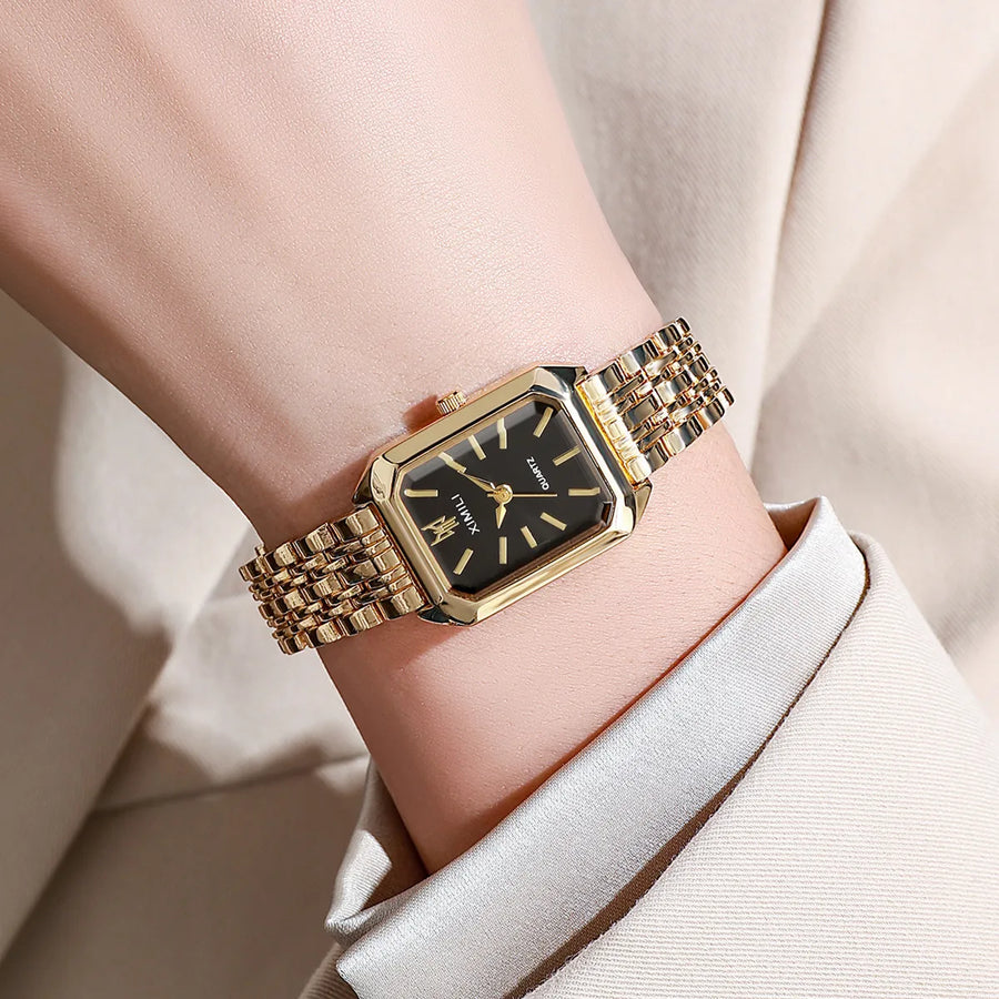 Women's gold square quartz watch with white dial worn on wrist
