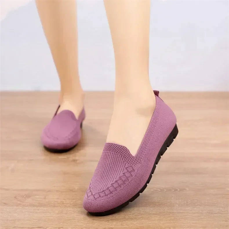 Purple loafers worn on a wooden floor with a light background