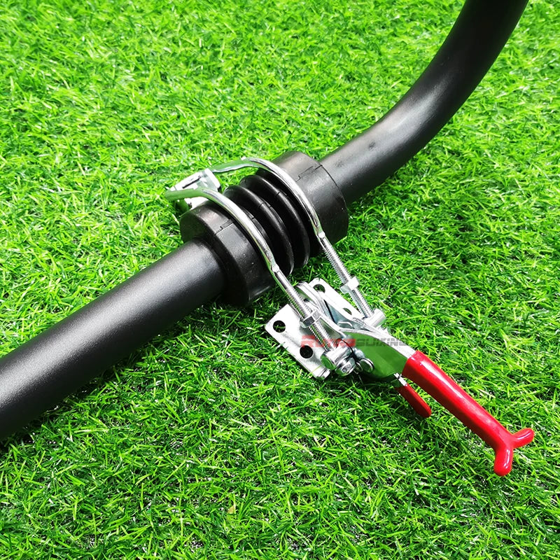A close-up of a black hose secured with a silver metal clamp and red handle tool, placed on bright green artificial grass.