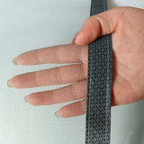 Hand holding a strip of black mesh fabric against a light background