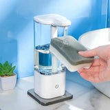 Automatic hand sanitizer dispenser with transparent tank dispensing soap onto a sponge on a marble bathroom countertop