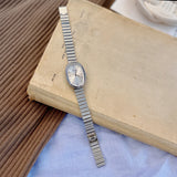 Silver watch on an open book with a textured surface