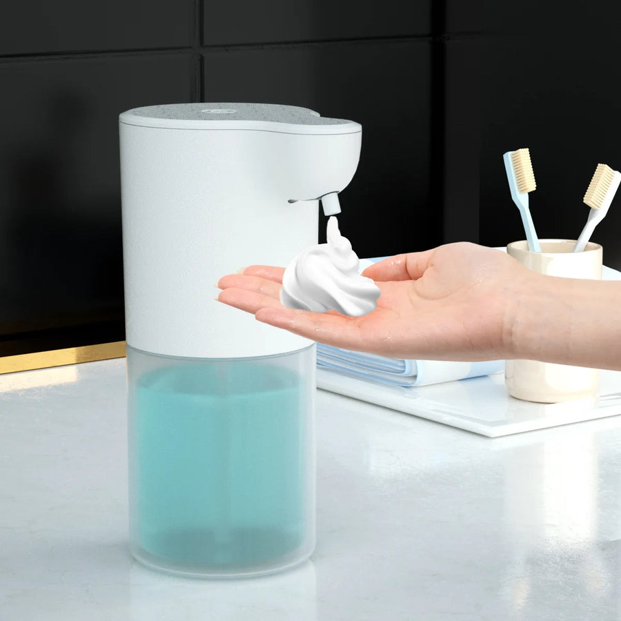 Touchless automatic foam soap dispenser with blue liquid tank dispensing foam into a hand on a bathroom counter