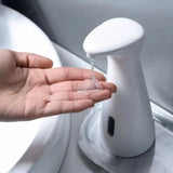 Hand pressing a white soap dispenser to release liquid soap.