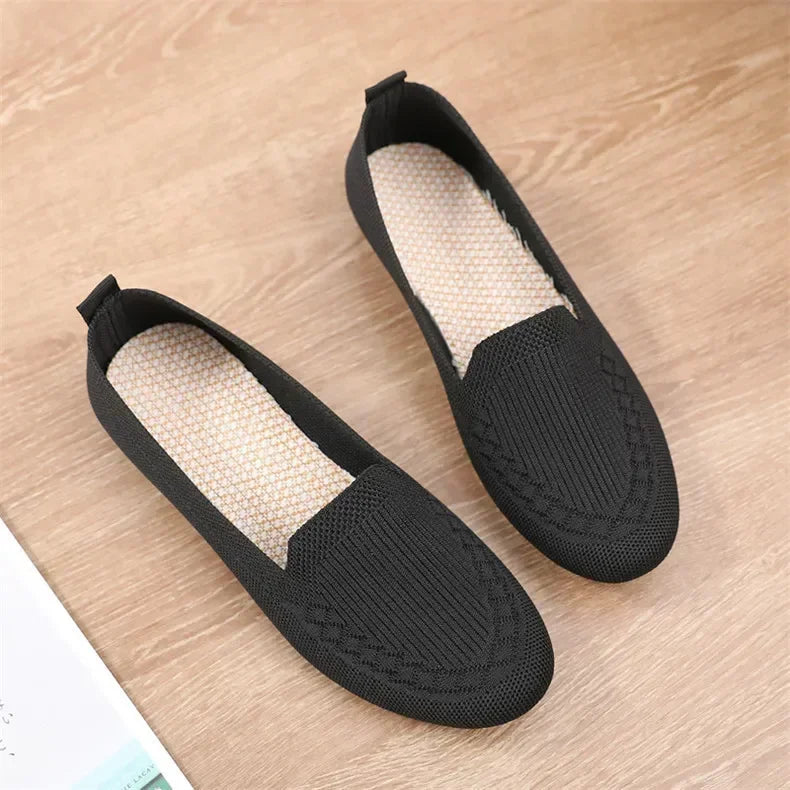 Pair of black slip-on shoes on a wooden surface