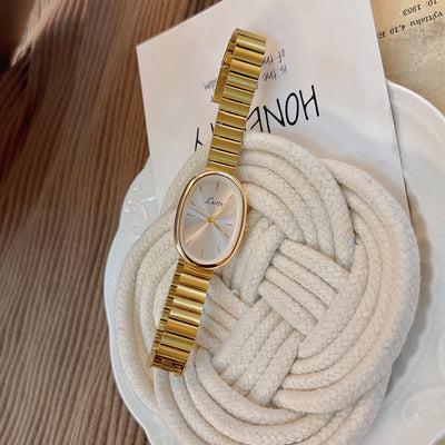 Gold watch on a textured surface with a blurred background