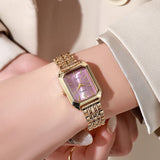 Close-up of women's gold quartz watch with pink dial worn on wrist