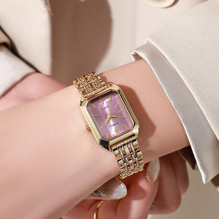 Close-up of women's gold quartz watch with pink dial worn on wrist