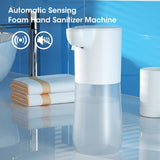Automatic sensing foam hand sanitizer machine in a bathroom setting with towels and a sink.