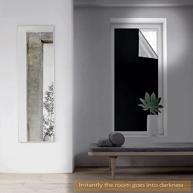 Living room with blackout window tint and a large mirror reflecting a stylish interior, showcasing privacy and darkness.