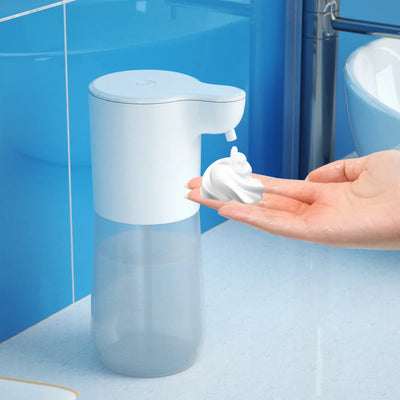 Automatic foam soap dispenser with transparent 350ml bottle dispensing rich foam onto a hand in a blue-tiled bathroom