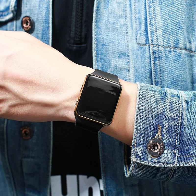 Person wearing a black LED digital sport watch with rose gold frame on wrist, denim sleeve, minimalist casual watch.