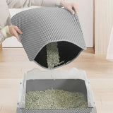 Person removing a gray double-layer cat litter trapping mat from a litter box on a wooden floor, easy-clean design