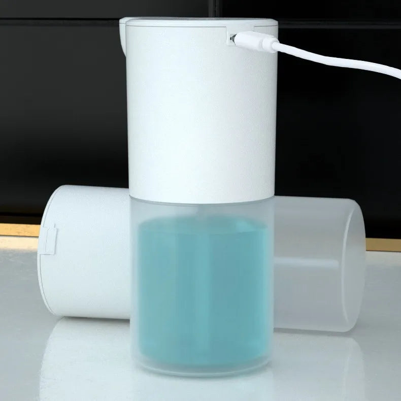 White automatic foam soap dispenser with transparent tank of blue liquid, USB charging cable connected