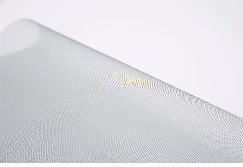 Close-up of a textured gray surface with small yellow particles on a white background