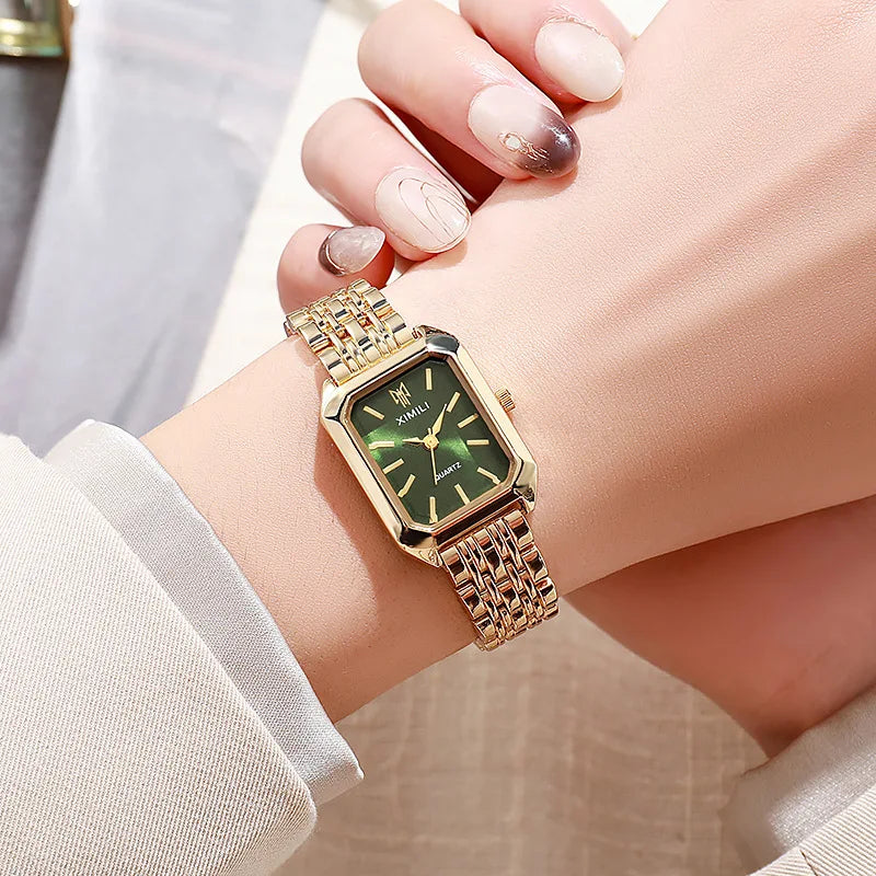 Women's gold quartz watch with green dial on wrist