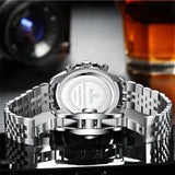 Men's silver quartz dress watch with detailed design on reflective surface, blurred background
