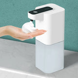 White soap dispenser dispensing soap onto a hand against a teal wall.
