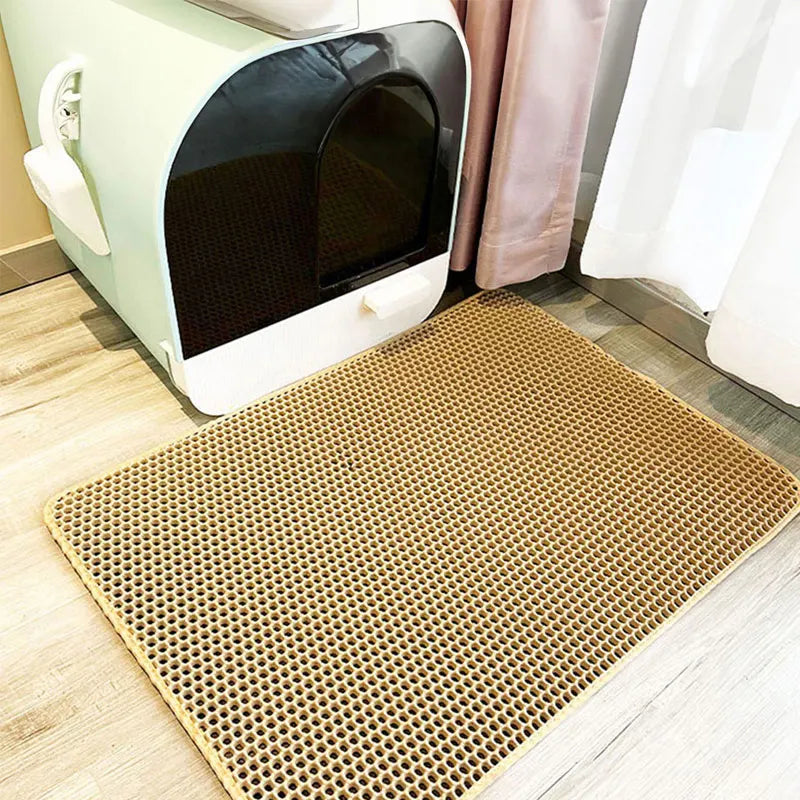 Cat litter box with a perforated honeycomb double-layer cat litter trapping mat underneath on a wooden floor